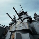 Close-up view of USS Alabama battleship's deck and cannons under a clear sky.