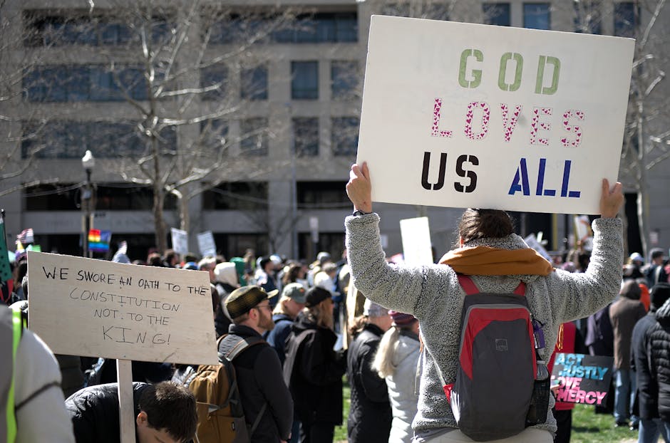 A crowd gathers for a protest in Baltimore holding signs promoting love, equality, and constitutional rights.