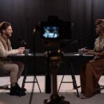 Two adults engaging in a podcast discussion in a studio with recording equipment.