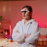 Female scientist wearing headband magnifier in lab coat, standing in modern laboratory with test tubes.