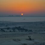 Sunrise over an industrial landscape with oil pumps.