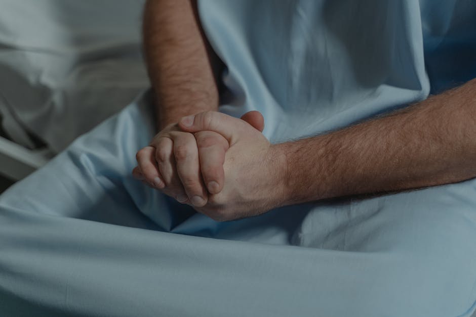 Close-up of a patient in a hospital setting, hands clasped, conveying emotion.