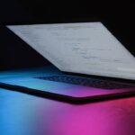 Open laptop with code on screen, neon lighting
