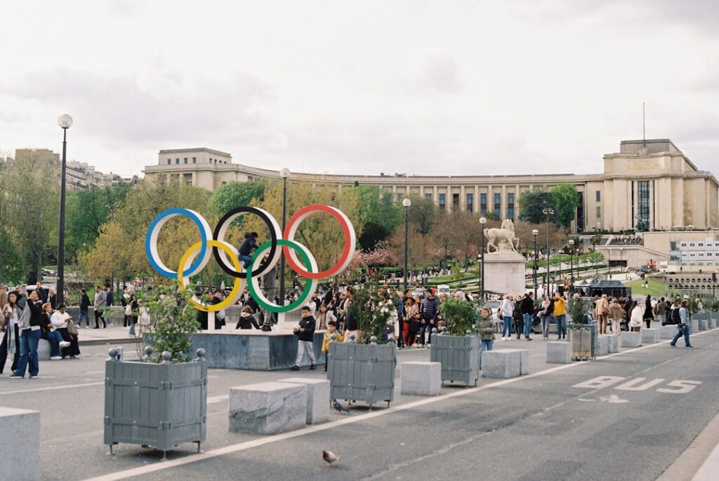 Olympic rings displayed with buildings in background.
