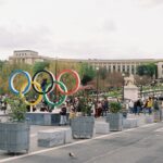Olympic rings displayed with buildings in background.
