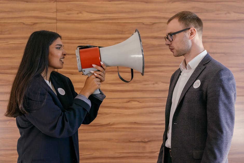 A woman using a megaphone to confront a man in a suit indoors, symbolizing political debate.