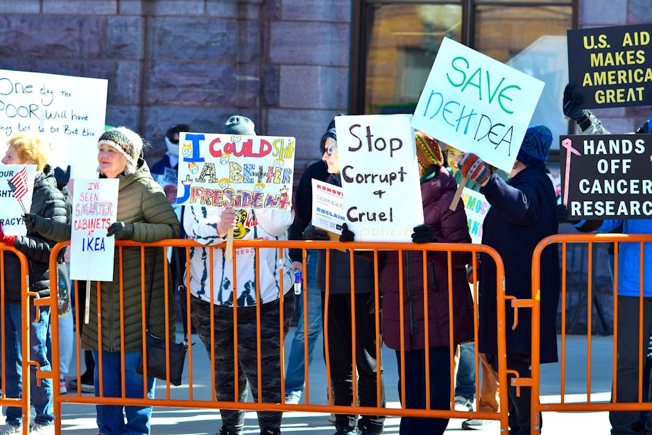 A group of people holding signs in a street protest, expressing dissent against political policies.