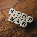 Dice with 'STOP WAR' on a vintage world map signifies peace.