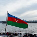 The azerbaijani flag waves above the water.