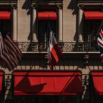 A classic building facade featuring US, French, and UK flags with vibrant red awnings.