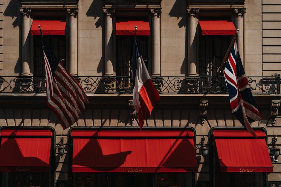 A classic building facade featuring US, French, and UK flags with vibrant red awnings.