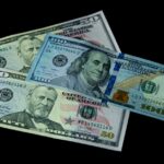 High-quality image of US 50 and 100 dollar bills on a black background, symbolizing wealth and economy.