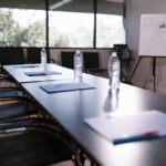 Spacious conference room with water bottles and notes on a wooden table ready for a meeting.