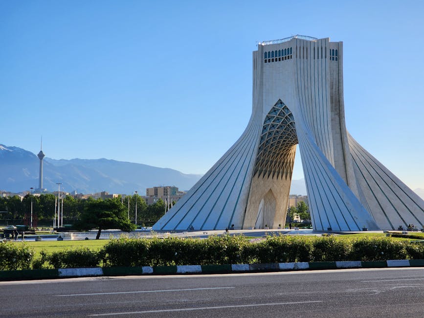 Capture of the iconic Azadi Tower in Tehran with a mountainous backdrop and clear sky.