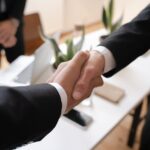 Close-up of a handshake between two professionals in a business setting, symbolizing agreement.