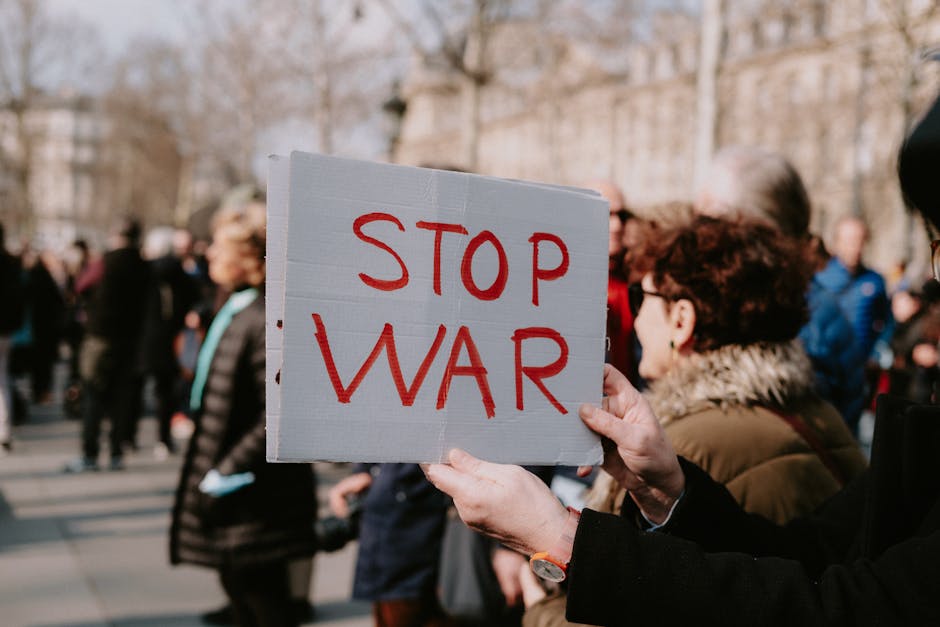 Crowd of people in a peaceful protest holding a 'Stop War' sign outdoors.