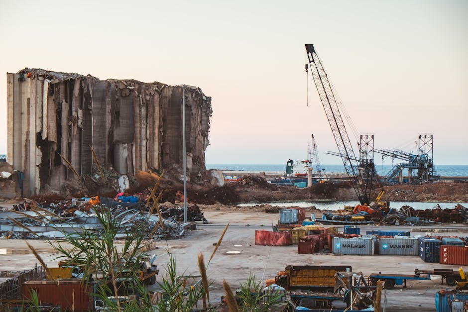 View of destruction and debris at Beirut port with cranes and sea in the background.