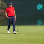A male golfer in red shirt on a golf course at Saudi International event.