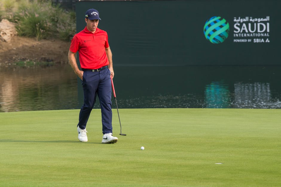 A male golfer in red shirt on a golf course at Saudi International event.