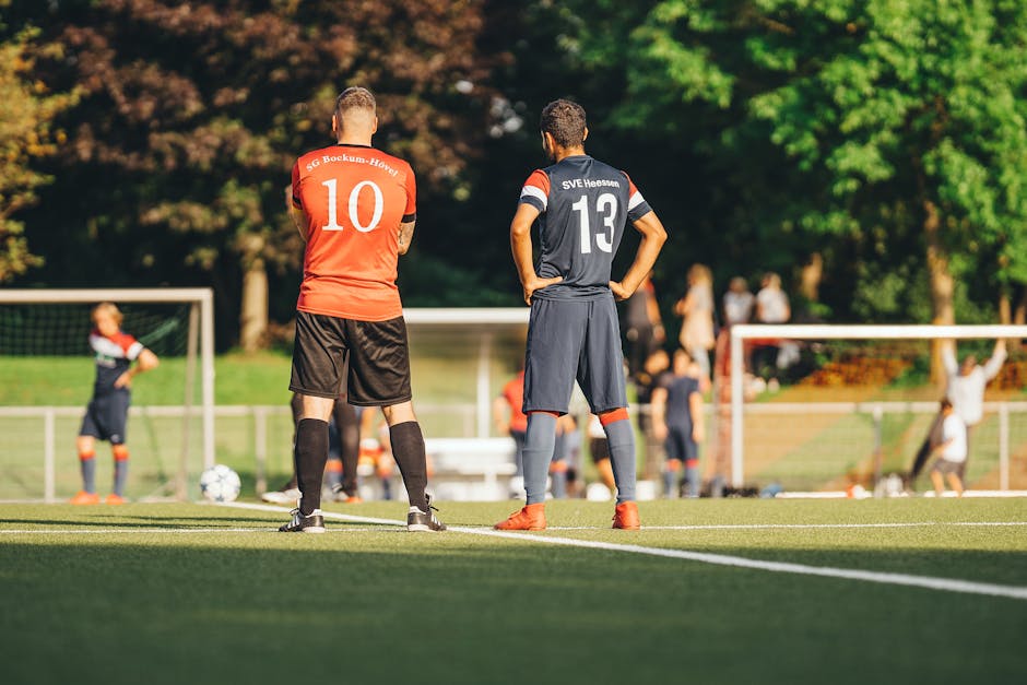 Soccer players in team jerseys standing on the field ready for the game.