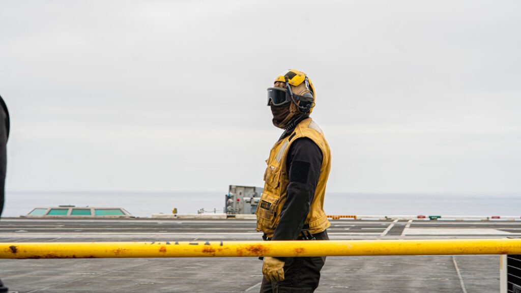 A military personnel stands on a ship's deck.