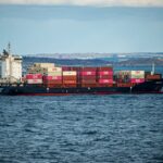A large container ship transports cargo across the open sea under a clear sky. Ideal for shipping and logistics themes.