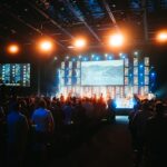 a crowd of people in a room with large screens and lights