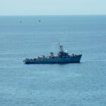 A military ship navigating the calm blue ocean under a clear sky, showcasing nautical power.