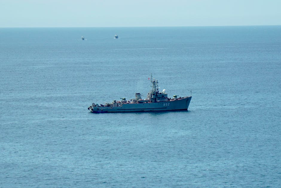 A military ship navigating the calm blue ocean under a clear sky, showcasing nautical power.
