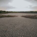 Aerial view of a cracked, dry landscape under a clear sky, highlighting climate change impact.