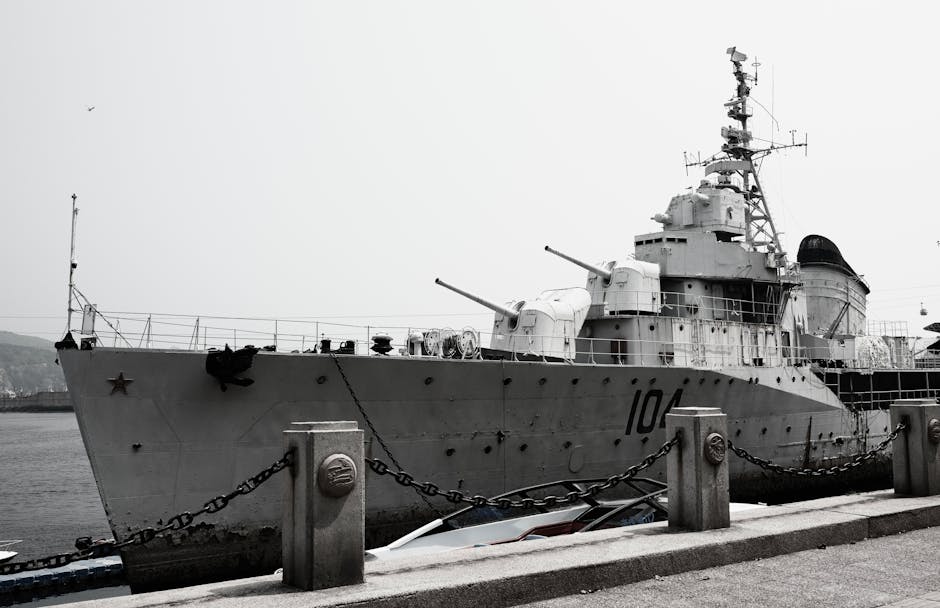 A large naval destroyer ship docked at a harbor under a gray sky.