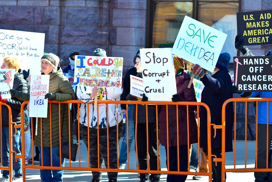 A group of people holding signs in a street protest, expressing dissent against political policies.