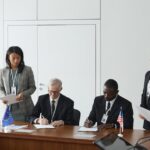 Business leaders signing a significant agreement in a conference room setting.