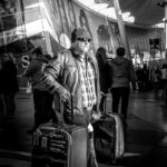 grayscale photo of standing man between luggage bags