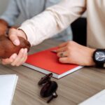 Close-up of a handshake over a desk with documents, signifying partnership.