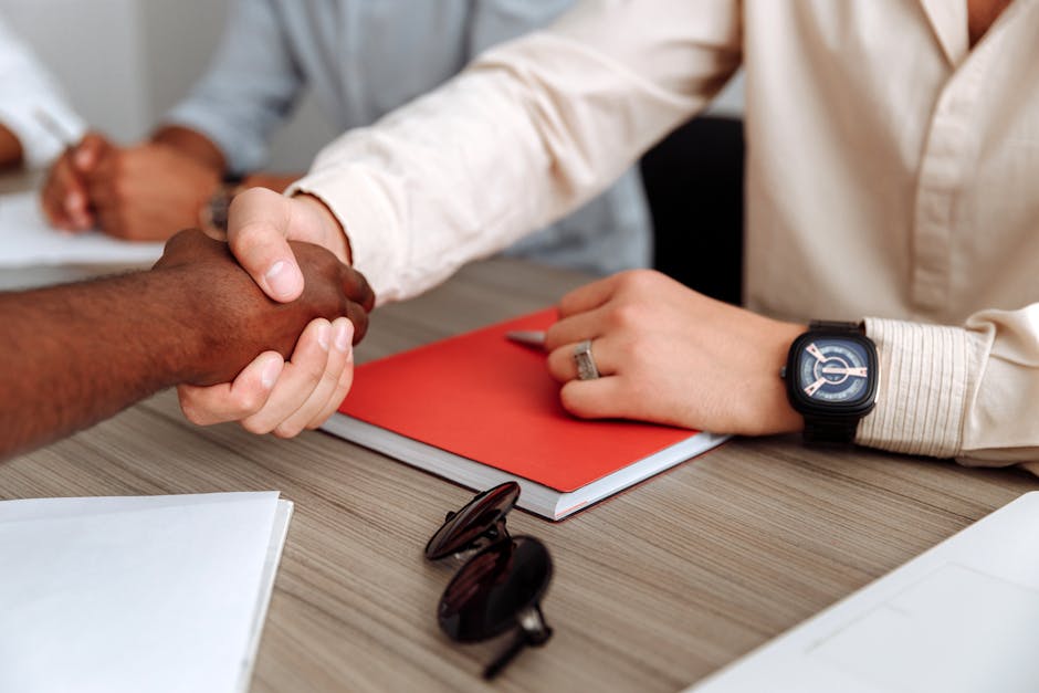Close-up of a handshake over a desk with documents, signifying partnership.