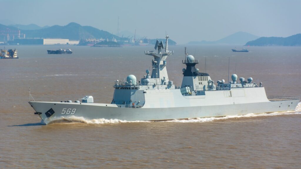 A modern gray warship sails on the ocean.
