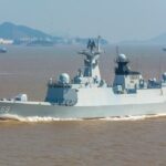 A modern gray warship sails on the ocean.