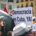 A vibrant street protest advocating for democracy in Cuba with visible signs.