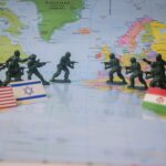 Toy soldiers face off on world map with flags.