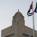 A traditional fortress with UAE flags at sunset in Abu Dhabi, showcasing architectural heritage.