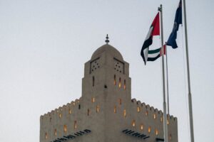 A traditional fortress with UAE flags at sunset in Abu Dhabi, showcasing architectural heritage.