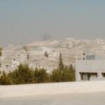 Buildings on a dusty, arid hillside under a hazy sky.