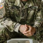Close-up image of a soldier wearing a camouflage military uniform, displaying patches and insignia.