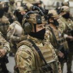 Group of soldiers in tactical gear standing in formation during a military operation.