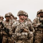 A diverse group of soldiers in camouflage uniforms standing with rifles.
