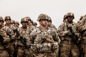 A diverse group of soldiers in camouflage uniforms standing with rifles.