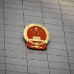 Close-up of the Chinese national emblem on a large concrete building facade, symbolizing government presence.