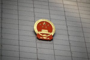 Close-up of the Chinese national emblem on a large concrete building facade, symbolizing government presence.