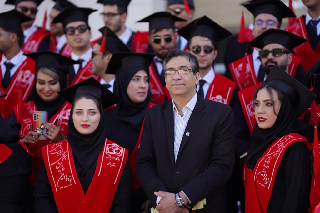 Graduates and a man pose for a photo.
